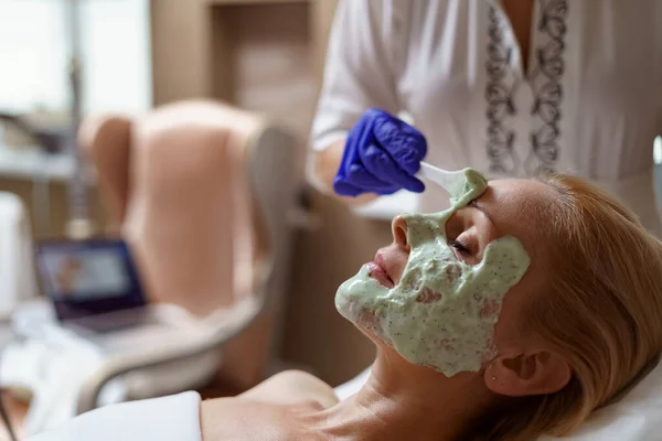 Cosmetician experiente está aplicando máscara saudável na pele feminina — Fotografia de Stock