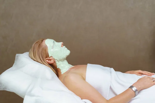 Experienced cosmetician is applying healthy mask on female skin — Stock Photo, Image