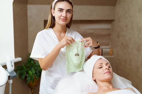 Tapasztalt kozmetikus alginát maszkot tart a kezében az eljárás után — Stock Fotó