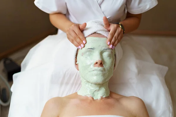 Ervaren schoonheidsspecialiste verwijdert alginaat masker van een gezicht van een blanke vrouw. — Stockfoto