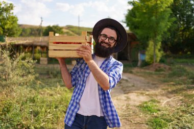 Omzunda taze domateslerle yürüyen çiftçi.