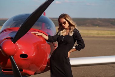 Uçak arka planında poz veren büyüleyici bir kadın.