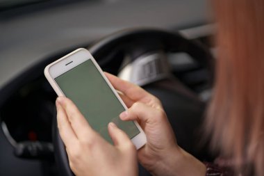 Kadın elleri araba kullanırken akıllı telefon kullanıyor.