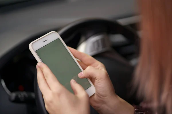 Mãos de mulher usando smartphone enquanto dirige — Fotografia de Stock