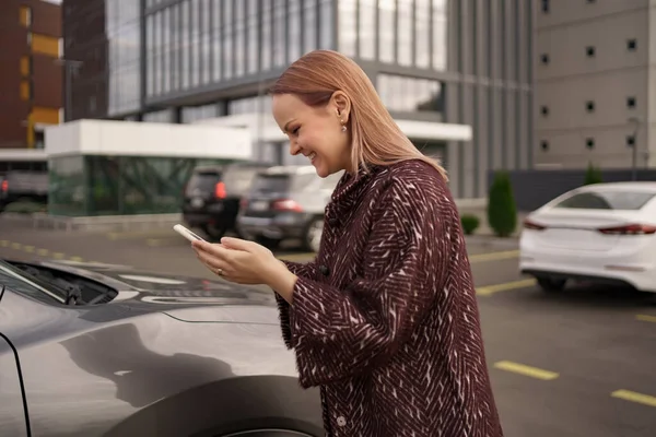 Mujer de pie hablan teléfono de uso en la ciudad cerca de coche gris —  Fotos de Stock