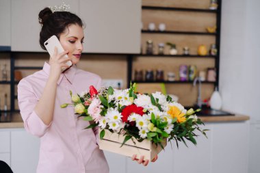 Genç çiçekçi dizüstü bilgisayara bakıyor ve telefona cevap veriyor.