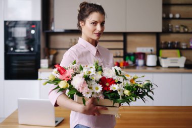 Güzel bir çiçek kompozisyonuyla gülümseyen bir kadın portresi.