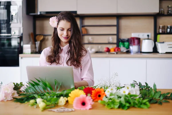 Portret van het werken potige brunette met bloemen en laptop aan tafel — Stockfoto