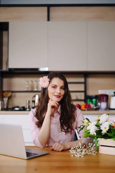 Portret van het werken potige brunette met bloemen en laptop aan tafel — Stockfoto