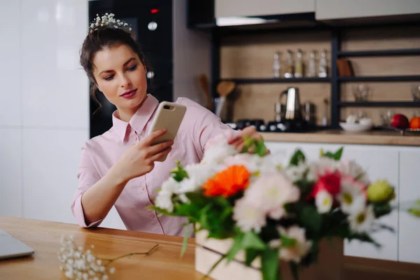 Joven florista mirando a la computadora portátil y respondiendo a la llamada telefónica — Foto de Stock