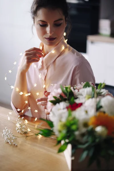 Florista mujer piensa cómo decorar flores con luces led — Foto de Stock