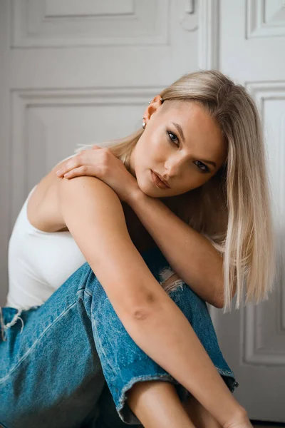 Mulher bonita posando enquanto se situa perto da porta branca em casa — Fotografia de Stock