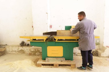 Erkek marangoz atölyede odun kesmek için testere kullanıyor.