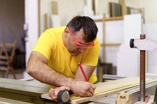 Carpinteiro que toma a medição de uma prancha de madeira com lápis e régua — Fotografia de Stock