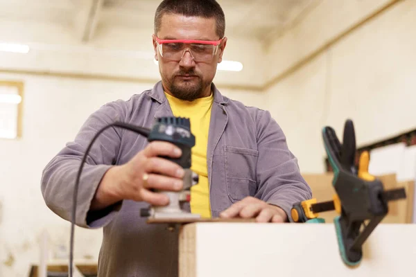 Timmerman met elektrische schuurmachine in de werkplaats — Stockfoto