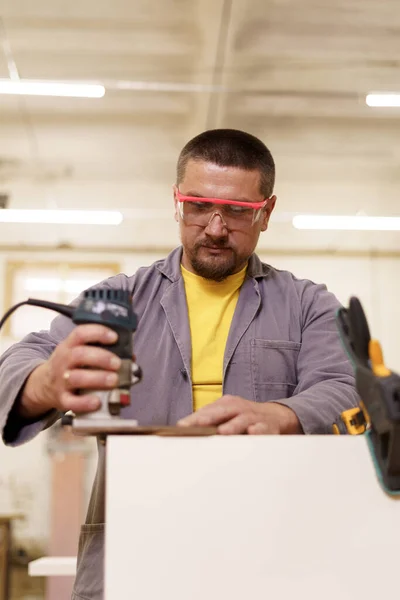 Timmerman met elektrische schuurmachine in de werkplaats — Stockfoto