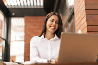 İşine odaklan. Genç ve güzel bir kadın otururken dizüstü bilgisayarını kullanıyor. Güzel, zeki, sevimli, çekici, zarif bayan ev sahibi içeride online toplantı yapıyor.