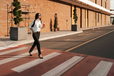 İş kadını işe ara veriyor ve Zebra 'da karşıdan karşıya geçerken dinleniyor. Elinde kahveyle iş merkezine gidiyor..