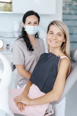 Hasta dişçi, kameraya bakıyor.