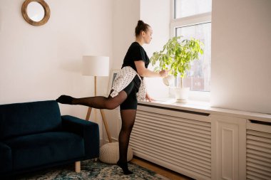 Çiçekleri sularken bale yapan güzel bir bayan.