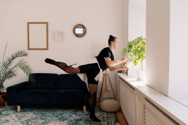 Çiçekleri sularken bale yapan güzel bir bayan.