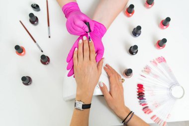 Güzellik salonunda manikürcü müşteriyi tedavi ediyor. Manikür, çivi boyası.