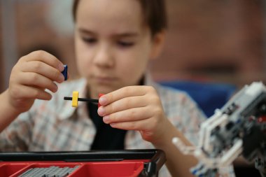 Akıllı okul çocuğu masada oturuyor ve robot bir cihaz yapıyor.