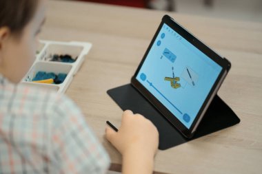 Çocuk tam fonksiyonel robot yapıyor ve onu okul robotları için tabletle programlıyor.