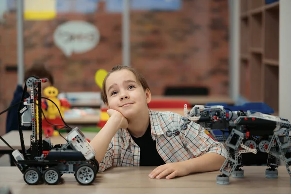 Smart schoolboy sitting at the table and constructing a robotic device