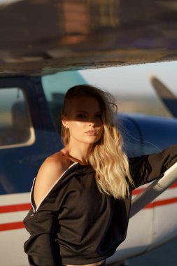 Uçağın yanında spor kıyafetiyle poz veren bir model.