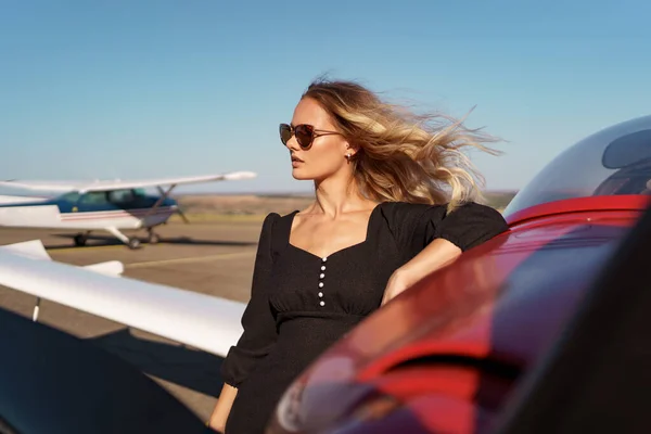 Schöne Dame mit Sonnenbrille posiert in der Nähe von Flugzeug — Stockfoto