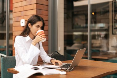 Esmer kadın laptopla çalışırken kahve içiyor.