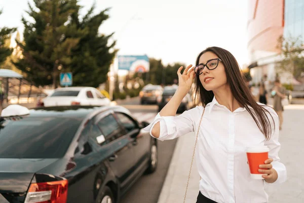 Joven empresaria cogiendo un taxi con un café para llevar —  Fotos de Stock