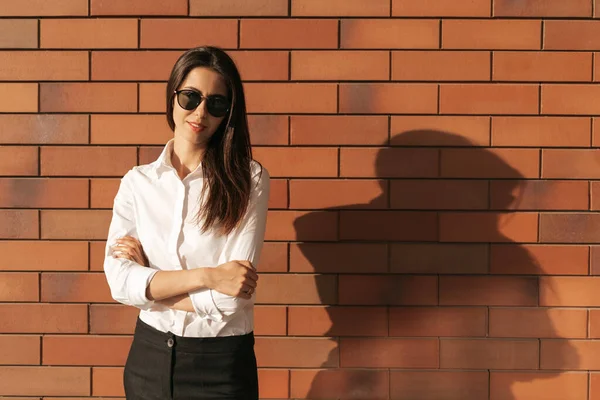 Fiatal nő portré tégla háttér napszemüveg — Stock Fotó