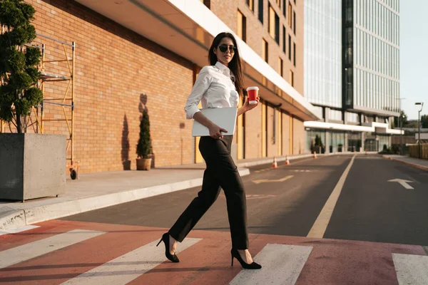 Mulher de camisa branca segurando um café para atravessar a rua — Fotografia de Stock