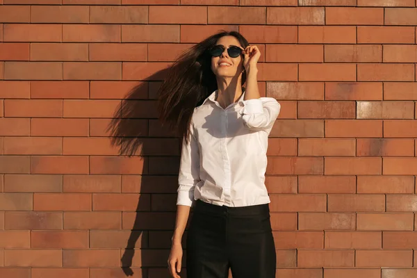 Jovem mulher retrato no fundo de tijolo em óculos de sol — Fotografia de Stock