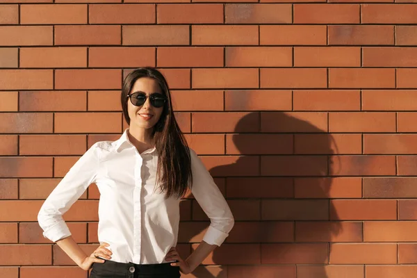 Retrato de mujer joven sobre fondo de ladrillo en gafas de sol —  Fotos de Stock