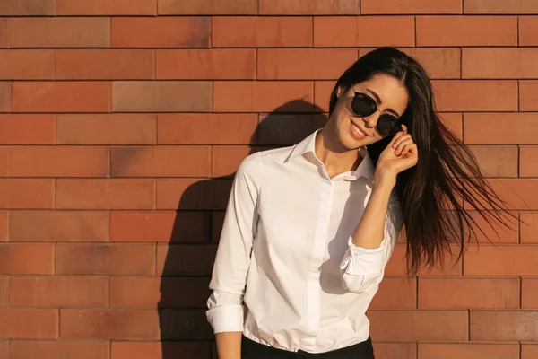 Fiatal nő portré tégla háttér napszemüveg — Stock Fotó