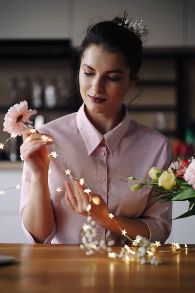 Florista mujer piensa cómo decorar flores con luces led — Foto de Stock
