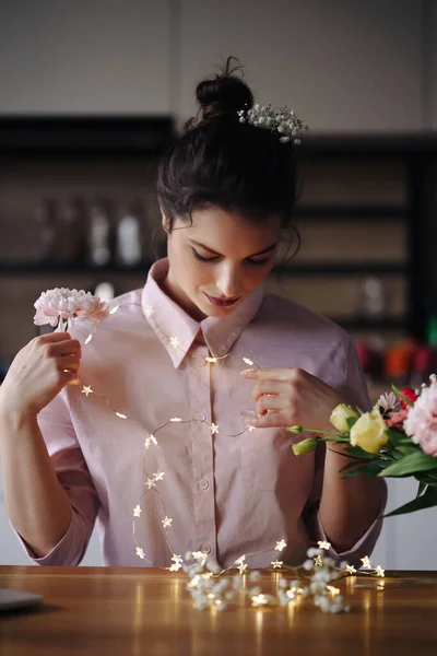 Florista mujer piensa cómo decorar flores con luces led — Foto de Stock