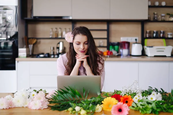 Portret van het werken potige brunette met bloemen en laptop aan tafel — Stockfoto