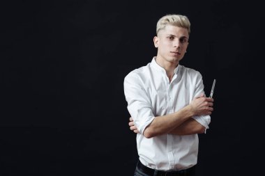 Kuaför aksesuarlarıyla ayakta duran erkek stilistin portresi.