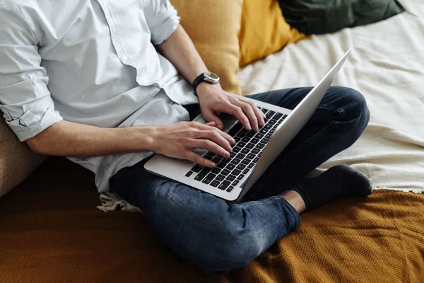 Trabajo remoto. Hombre trabajando en el ordenador portátil sentado en el sofá en casa — Foto de Stock