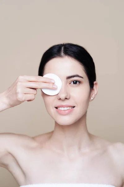 Young brunette woman removing makeup from her face — Stock Photo, Image