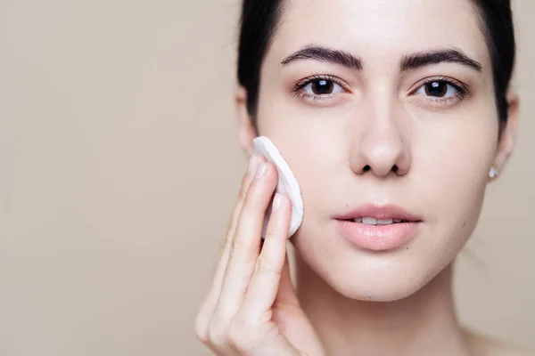 Young brunette woman removing makeup from her face — Stock Photo, Image