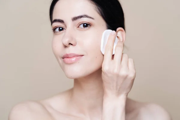 Young brunette woman removing makeup from her face — Stock Photo, Image