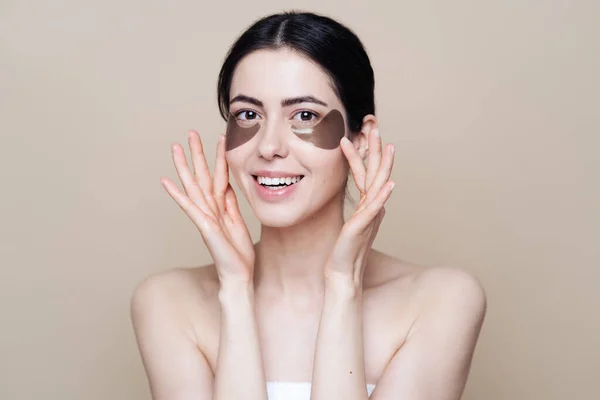 Young beautiful woman with clean fresh facial skin, uses eye patches