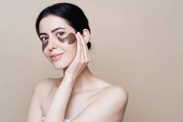 Young beautiful woman with clean fresh facial skin, uses eye patches — Stock Photo, Image