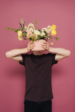 Bir demet çiçek tutan mutlu yakışıklı genç adam..