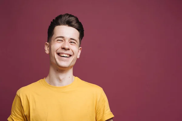 Közelkép portré mosolygós jóképű fickó barna pólóban elszigetelt bíbor háttér — Stock Fotó